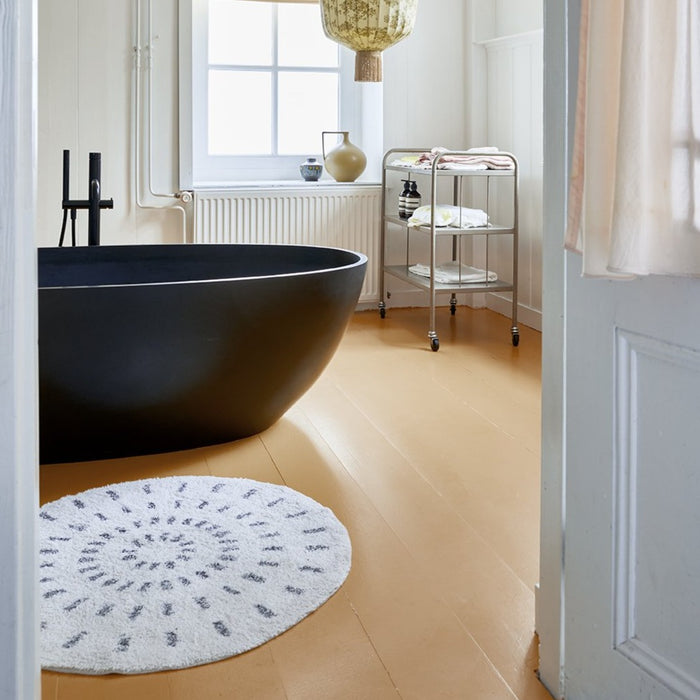 bathroom with black bath tub and round swirl rug