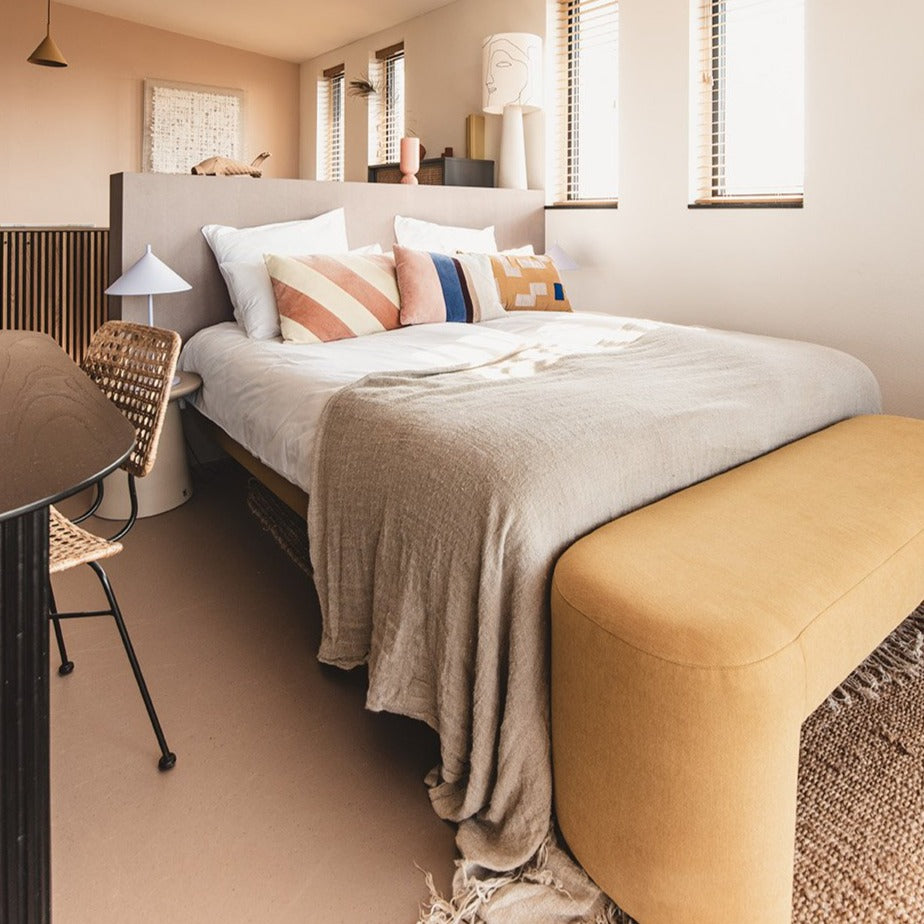 king size bed with natural linen duvet and yellow bedbench