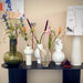black oval console table with table lamp and flower vases