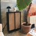 black sliding door cabinet with cane webbing doors in an industrial style loft with a large plant and orange tiled kitchen block
