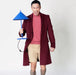 man wearing pink shirt, maroon coat holding a blue metal triangle table lamp