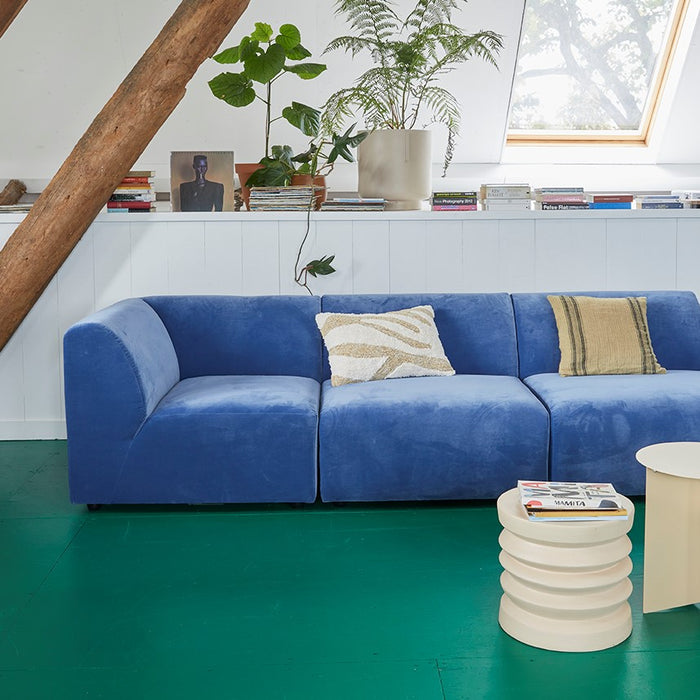 living room with a green floor, blue sofa and natural linen pillows in light colors