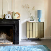 olive green cabinet with ice blue table lamp and flower vases