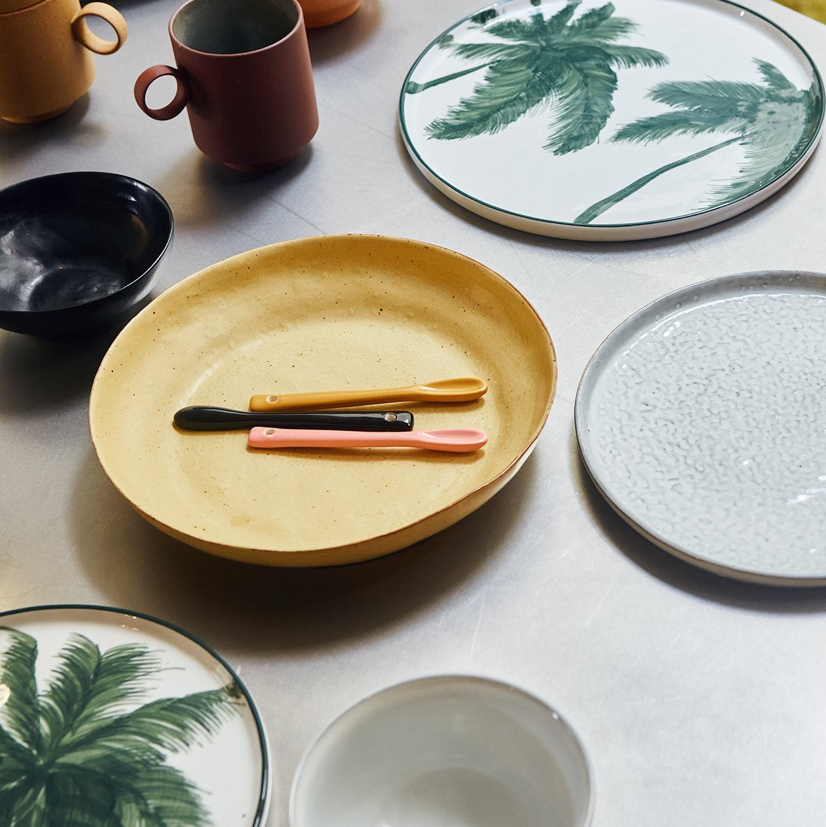 yellow plate with yellow pink and black ceramic spoons