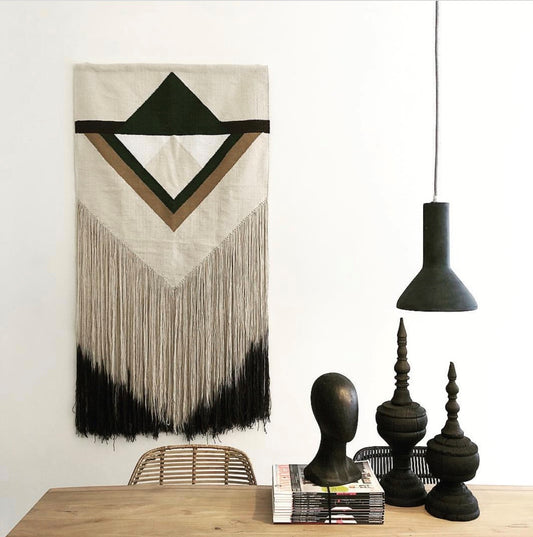 black concrete single pendant light over a wooden table next to a modern wall hanging 