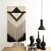 black concrete single pendant light over a wooden table next to a modern wall hanging 
