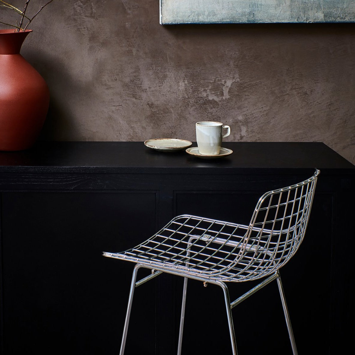 chrome colored counter bar stool against a black bar 