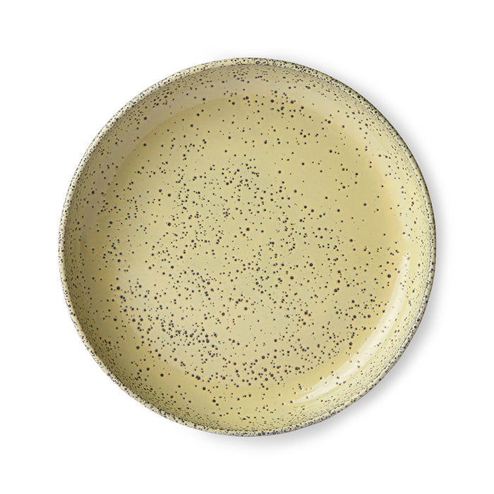 round yellow stoneware pasta plate with dark gray speckles