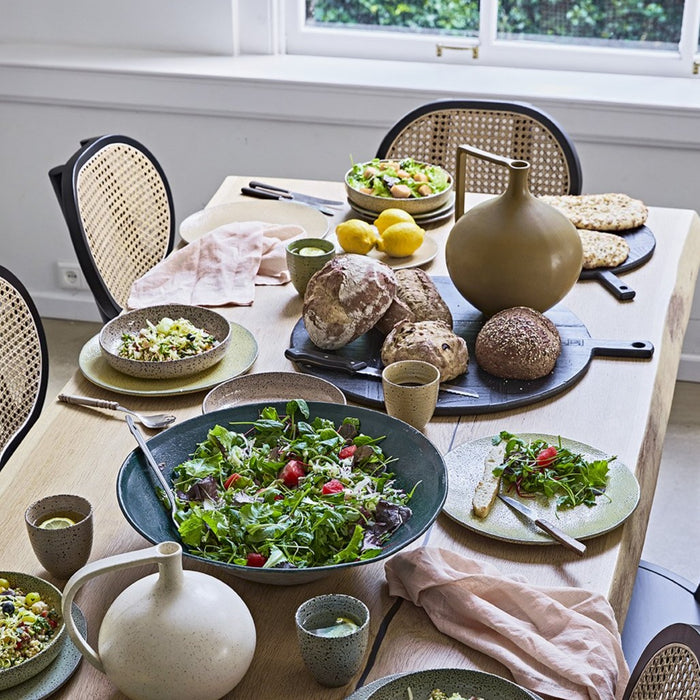 table setting with family style serving of salad and gradient ceramics in muted colors