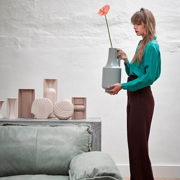 group of vases in earth tones and woman holding a green vase