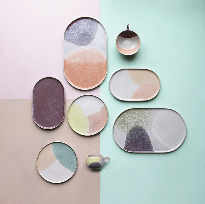 oval and round shaped stoneware plates with pastel colors on a color blocked table top