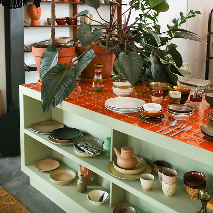 different style ceramics in open shelving in kitchen island with orange tiles