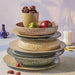 stack of gradient ceramics in different earth tones with fruit and vegetables
