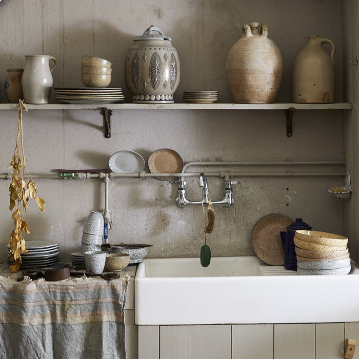 vintage style kitchen with stoneware plates mugs and vessels on open shelving