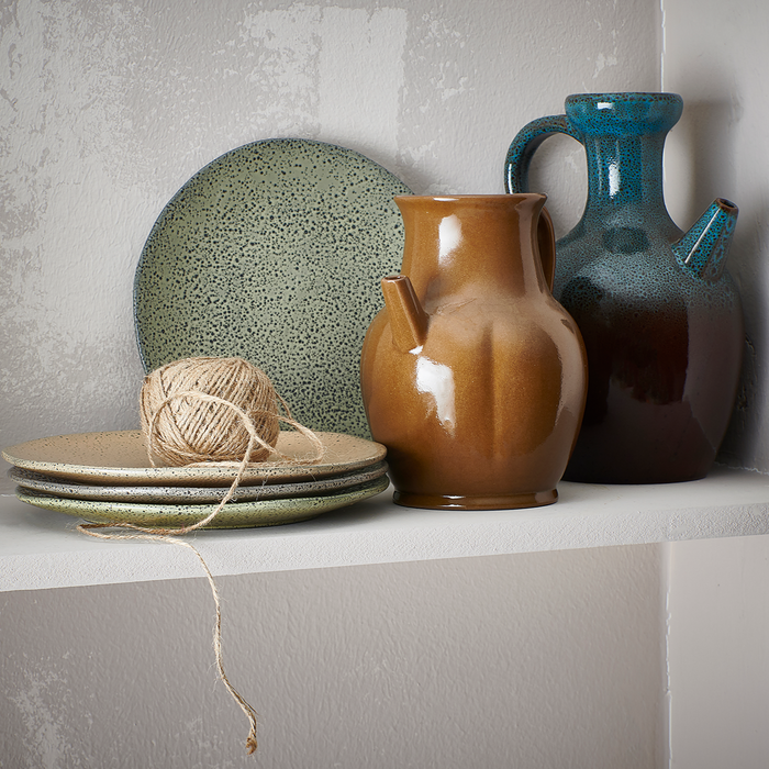 gradient ceramics plates in earth tones next to a brown and blue ceramic jar