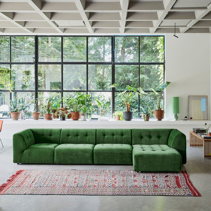 mid century modern style living room with large green sofa and a variety of planters with plants in window
