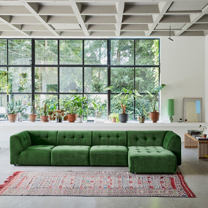 midcentury modern style living room with green sofa and flower vases in window
