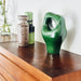 organic shaped green sculpture and vases in 70style on wooden surface