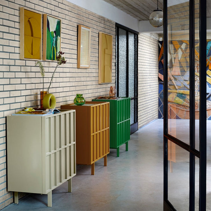 entryway with 3 different color credenza's and a earthenware circle vase in green
