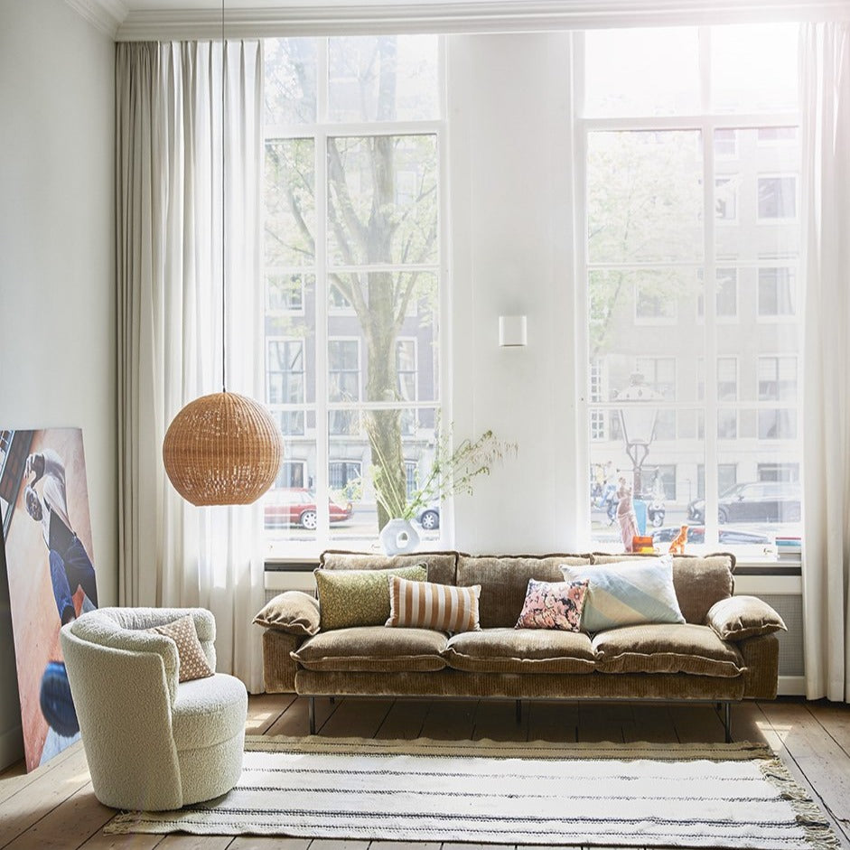 retro style ball pendant made of bamboo next to retro sofa with pillows