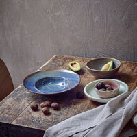 deep side plate with green inside and blue deep plate and bowl with half of an avocado