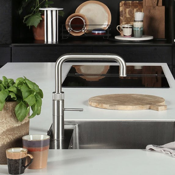 black kitchen with white counter top en dinner plates made of earth colored stoneware in rack