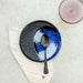 blue and black plate with black spoon on a marble tray