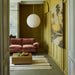 foyer with retro style velvet sofa, yellow walls and big bamboo and rice paper pendant light fixture