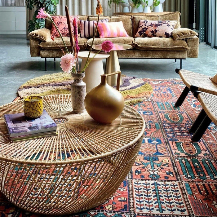 round coffee table made of handwoven wicker with vases and books 