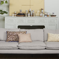 detail of beige fabric sofa with a fireplace filled with colorful ceramics