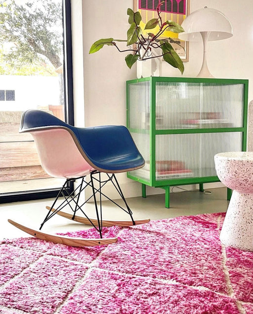 green credenza with ribbed glass sliding doors, a blue modern rocking chair and a pink area rug