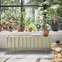 large window with plants in pots and a low sideboard with books