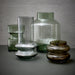 4 glass flower vases iin brown grey and green tones on a charcoal colored table