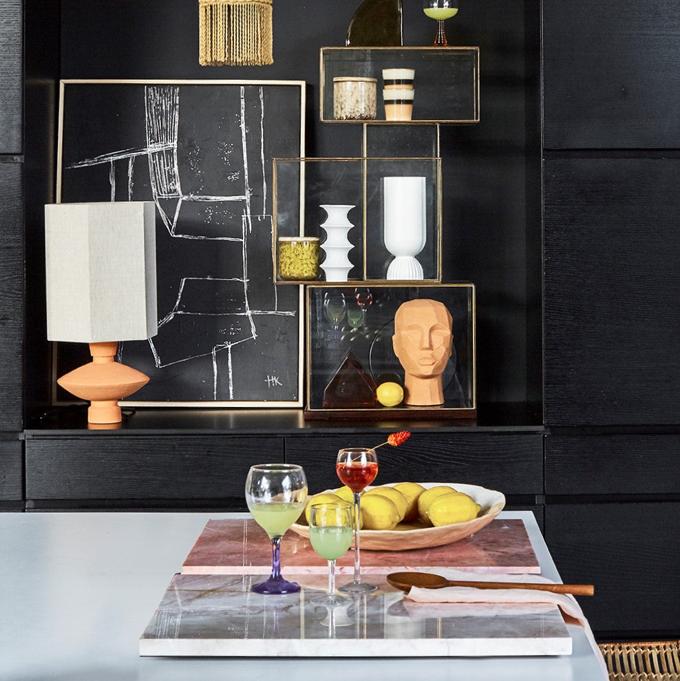 cblack walls with black art work, terracotta sculpture head and terracotta lamp with linen shade