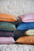 orange, pink, blue, brown and green lumbar shaped pillows in two sizes on two stacks