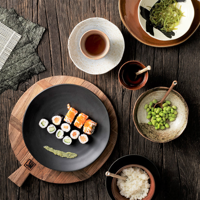 table with dinnerware and edema beans and sushi on black plate
