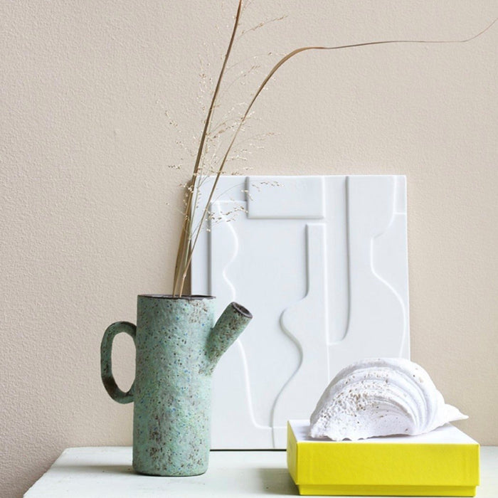 white abstract art panel made from stoneware with a ceramic jug and a yellow box