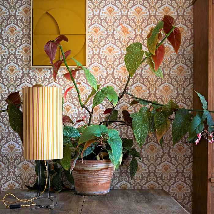 retro style striped table lamp on a table with a green plant behind it