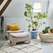bright living room with white walls, a blue metal side table, a natural rattan coffee table and a retro style pink ottoman with a matching lounge chair