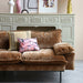 detail of a brown corduroy sofa with flower and linen pillows and a green fireplace mantel 