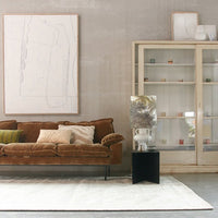 grey walls, brown sofa, white table lamp with jungle print lampshade on a black metal table