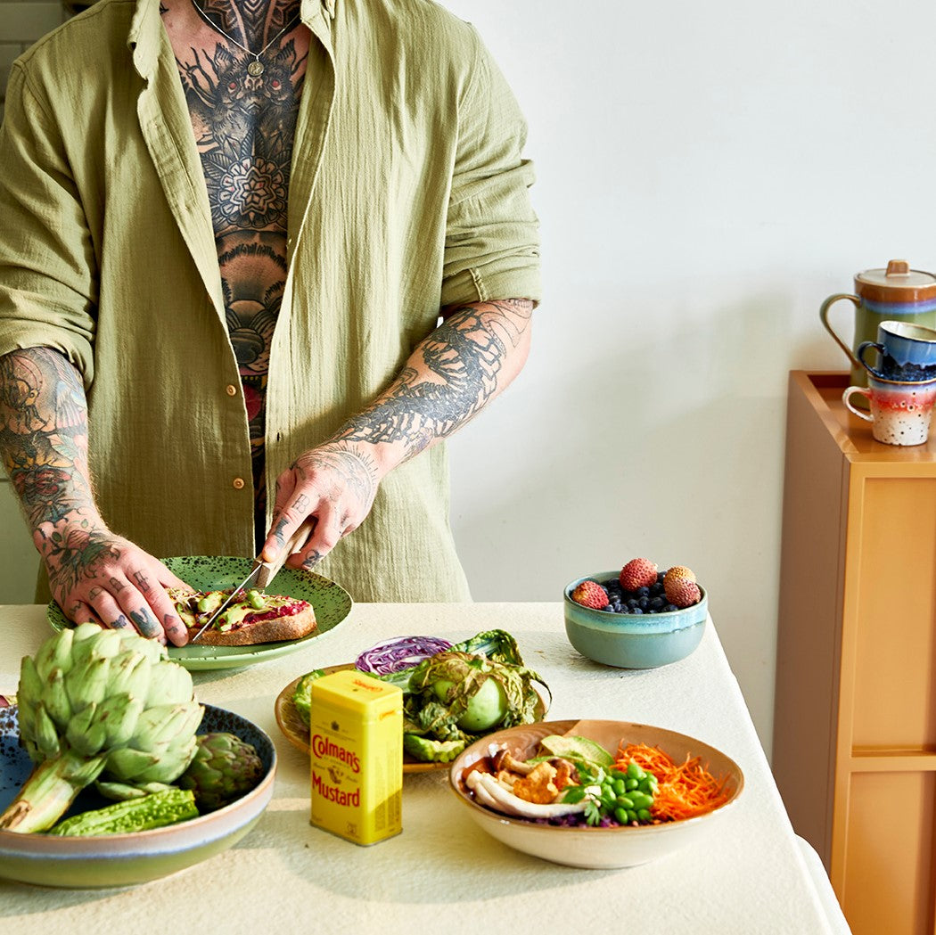 tattooed guy making avocado toast