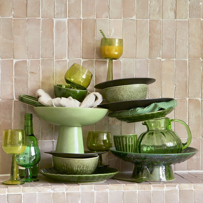 green bowl on foot in a stack with other green colored table ware