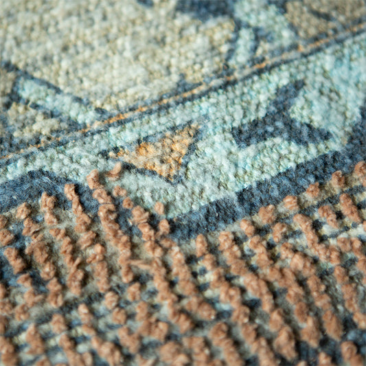 detail of square area rug with fringes and muted colors