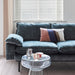 velvet sofa in a petrol blue color with a glass side table