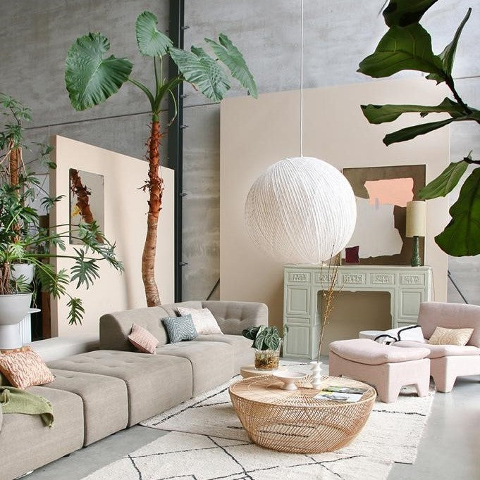 living room with pastel colors, a super large white hanging light and a wicker coffee table