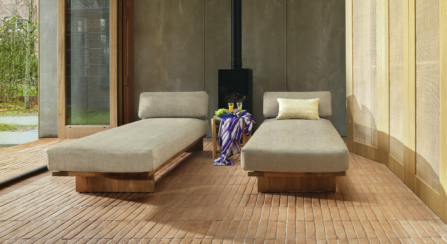 two teak wooden day bed with beige cushion in a sun room