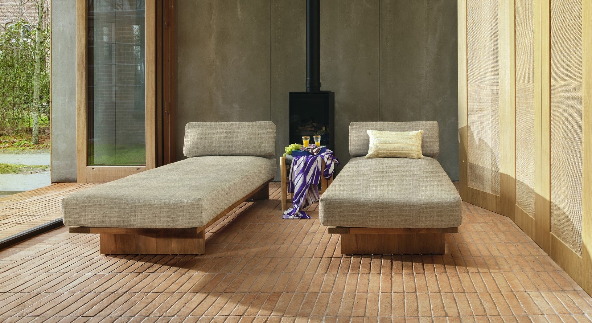 two teak wooden day bed with beige cushion in a sun room