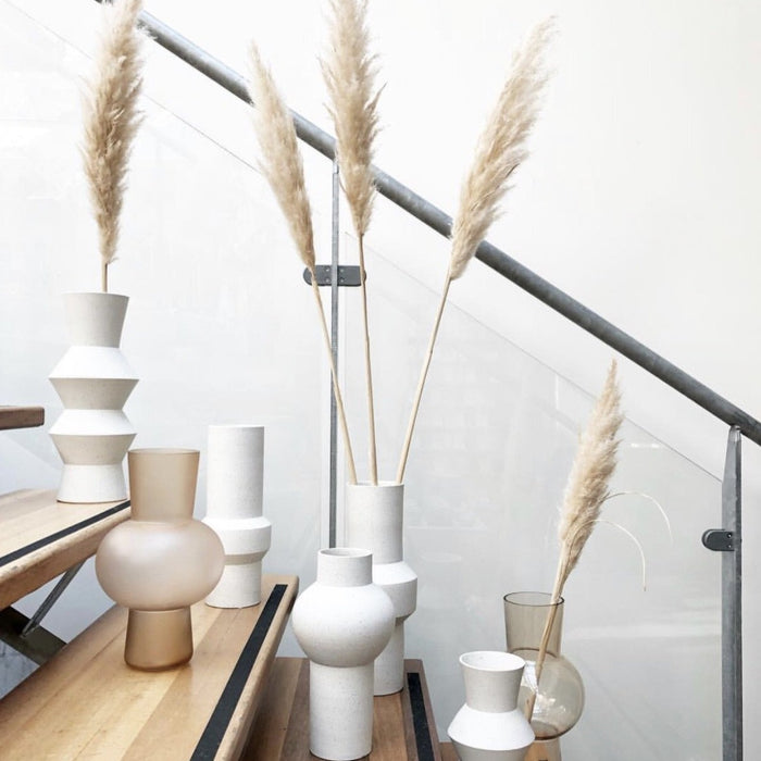 stairway with white spackled clay vases and one frosted glass vase in a peach color