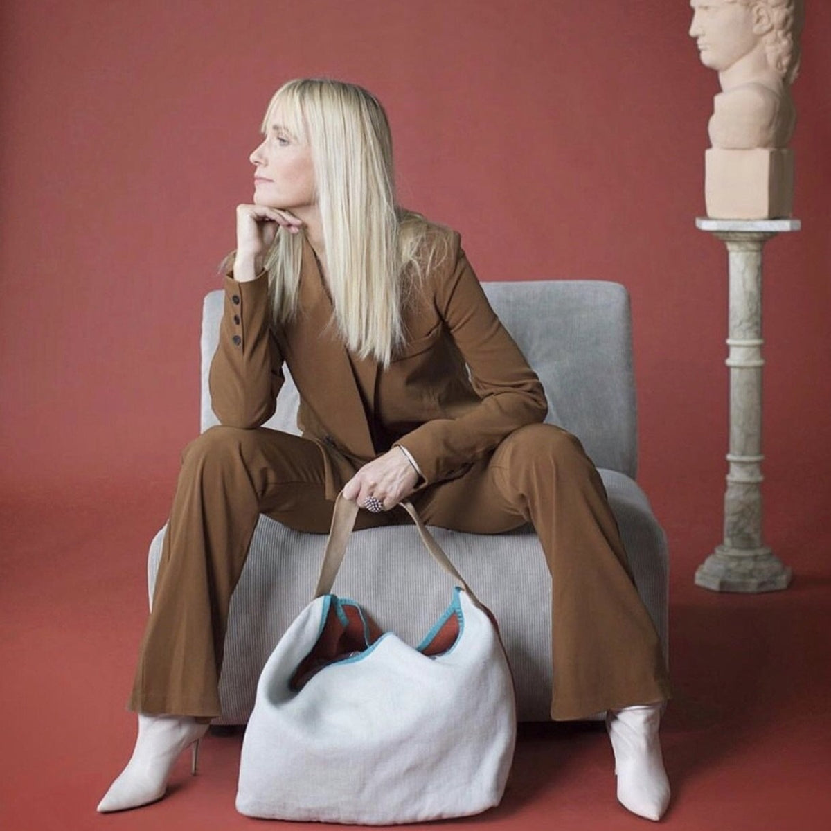 blonde woman in a brown suit with a white linen tote bag